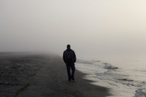 Lonely walker on grey, misty beach